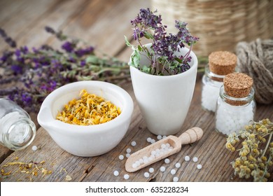 Mortar and bowl of dried healing herbs and bottles of homeopathic globules.  Homeopathy medicine concept. - Shutterstock ID 635228234