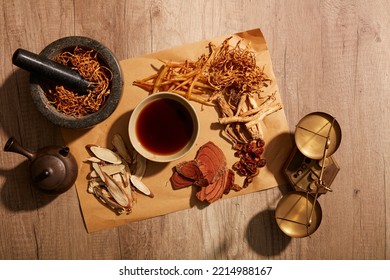 The mortar containing the cordyceps and herbs around the teacup on a wooden background - Shutterstock ID 2214988167