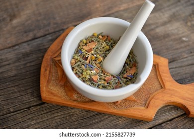 mortar with healing herbs, bouquet of daisy and clovers on wooden board, herbal medicine