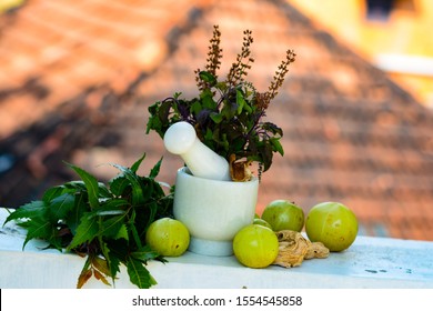 Mortar And Pestle ,Neem Leaves ,Amla, Tulsi Leaves, Dry Ginger Etc. On A Tiled House Background. Trivandrum, Kerala, India.