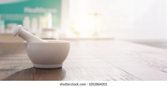 Mortar and pestle on the pharmacist's table and pharmaceutical products on the background - Powered by Shutterstock