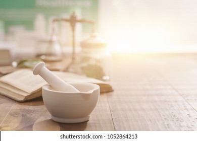 Mortar and pestle with pharmaceutical preparations's book and herbs on a wooden pharmacist table, traditional medicine and pharmacy concept