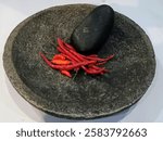 a mortar and pestle ready to grind or puree red chilies manually