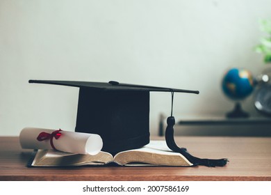 A mortarboard and graduation scroll on open books on the desk.education learning concept - Shutterstock ID 2007586169