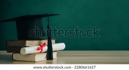 A mortarboard and graduation scroll, tied with red ribbon, on a stack of old battered books.Concept education congratulation. Graduation Ceremony. E-learning education.