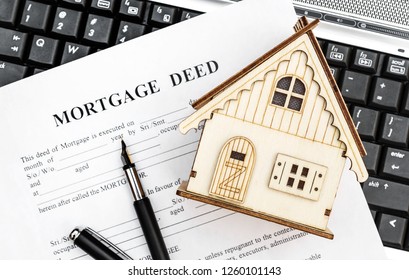 Mortgage Deed With Model Of House On Laptop Keyboard. Top View.