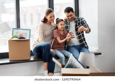 mortgage, family and real estate concept - happy mother, father and little daughter with house model and stuff in boxes moving to new home - Powered by Shutterstock