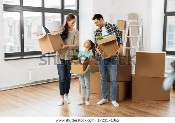 mortgage,\
family and real estate concept - happy mother, father and little\
daughter with stuff in boxes moving to new\
home