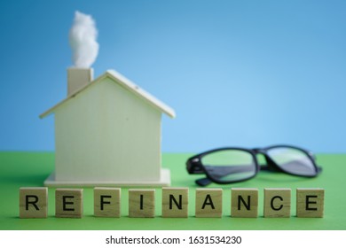 Mortgage And Home Refinance Conceptual With Wooden House On Green And Blue Background