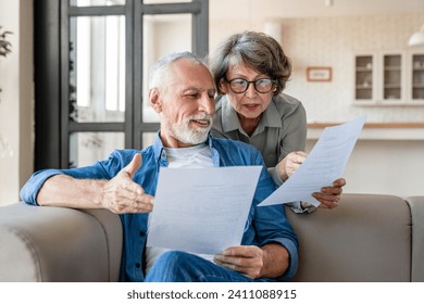 Mortgage loan debt transactions paying bills and documents. Caucasian senior old couple spouses reading marriage contract, doing paperwork, dealing with data at home - Powered by Shutterstock