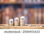 Mortgage loan or home equity loan, financial concept : Tiny model residential house perched atop coin stacks, depicting home loan or borrowing money to purchase a new home for first time homebuyer.	