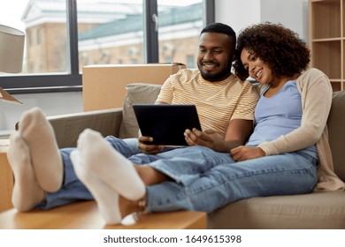 mortgage, people and real estate concept - happy african american couple with tablet pc computer sitting on sofa at new home - Shutterstock ID 1649615398