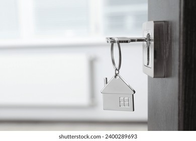 Mortgage and real estate. Open door with key and house shaped keychain against blurred background, space for text - Powered by Shutterstock