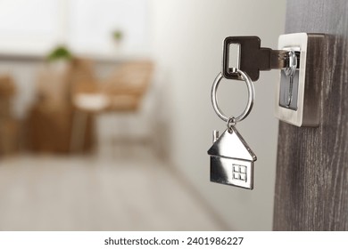 Mortgage and real estate. Open door with key and house shaped keychain against blurred background, space for text - Powered by Shutterstock