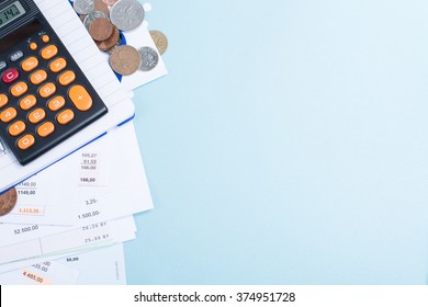 Mortgage and utility bills, foreign coins and calculator, different amounts, copy space, on blue background