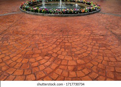 Mosaic Block Concrete Stamped Floor Exterior.Stone Brickwork Pattern On Outdoor Sidewalk Or Patio With Fountain Around With Flower Garden Background.