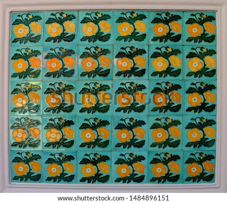 A mosaic of green tiles decorated with yellow flowers. These are typical of the tiles found on the facade of traditional Chinese Pernakan shop houses.