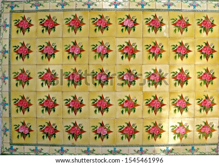 A mosaic of yellow tiles decorated with red flowers. These are typical of the tiles found on the facade of traditional Chinese Peranakan shop houses.
