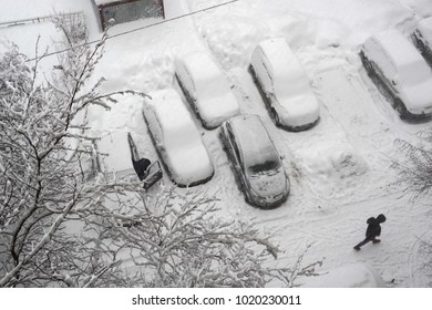 Moscow Courtyard After A Snowfall. The Car Enthusiast Is Trying To Get Inside His Car. Cars Parked In The Courtyard Are Covered With Snow. View From Above.