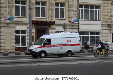 Moscow - July 15, 2020: Ambulance Car Is Driving Down The Street Near Building Whith Flags