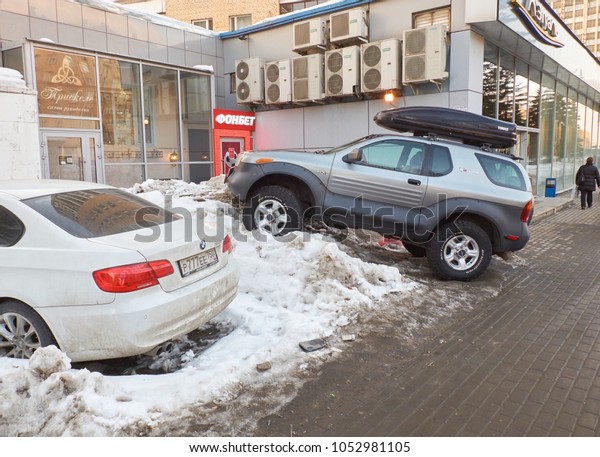 MOSCOW, MARCH, 22, 2018:\
?lose-up of off road car funny parked in a snow pile on winter city\
street. Extreme car parking problem humor concept. Parking place\
ansence