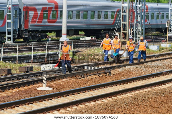 MOSCOW, MAY, 18, 2018: View of railway maintenance\
workes group with trolley doing rail tracks ultrasonic inspection\
and visual control and train cars in the background. Railroad\
people at work