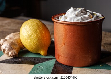 Moscow Mule Cocktail In A Copper Mug, Next To Sicilian Lemon And Fresh Ginger. Drink Decorated With Ginger Foam And Lemon Zest.