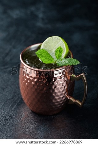 Moscow mule cocktail in a copper mug with lime and mint on dark kitchen table background