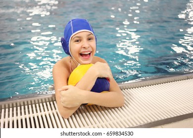 MOSCOW - NOV 17, 2016: Portrait of a happy young girl (with model releases) in an embrace with a ball for water polo in the pool