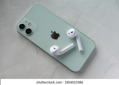 MOSCOW - NOV 17, 2020: Customer just opened brand new iPhone 12 mini (green color) ordered on a launch day and paired it with 1st gen AirPods