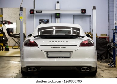 Moscow. November 2018. White Porsche Panamera At The Wheel Alignment Stand Of The Service Center. Sports Porsche, Executive Class Sedan In The Tuning And Repair Center.