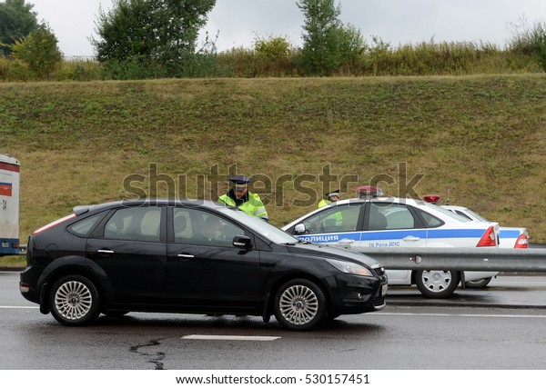 MOSCOW REGION, RUSSIA - AUGUST 27,2014: The\
inspector of traffic police check the documents of the driver on\
the track \