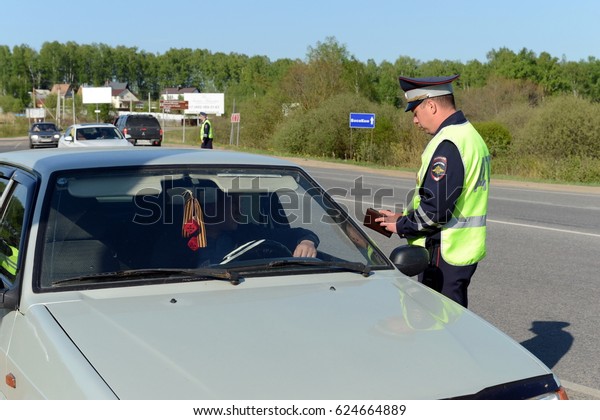 MOSCOW REGION, RUSSIA\
- MAY 14,2016:The officer of the police checks documents of the\
driver of the car.