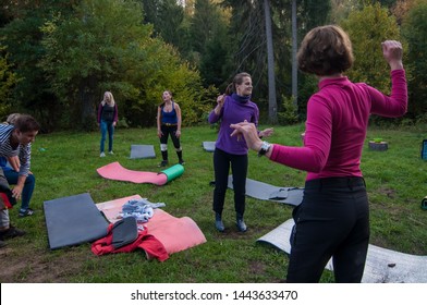 Moscow region, Russia - September 2014: group of men and women involved in sports and crossfit on mats in the Park - team building concept