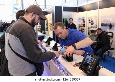 Moscow / Russia – 02 26 2017:The Consultant Shows A Bearded Man Fisherman New Chartplotter Garmin On The Stand At Exhibition 