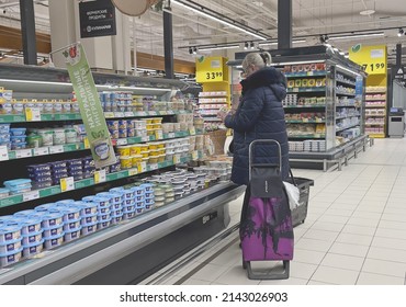 Moscow, Russia - 04.05.2022: A Woman Reads Information On A Soft Cheese Packaging In The Grocery Store. Dairy Products, Essential Goods. Inflation And Hyperinflation, Price Increase. Food Import.