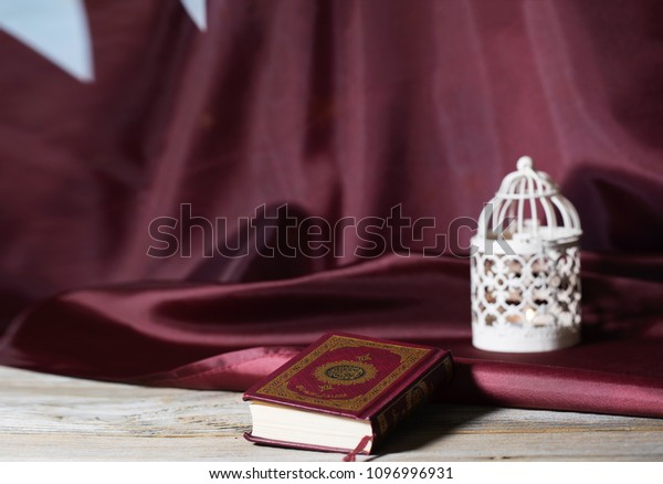 Moscow, Russia. 05/21/2018. Sacred book of Koran\
on a wooden surface. Flag of Qatar in the background. Tanslation-\
the book contains verses of\
Koran.