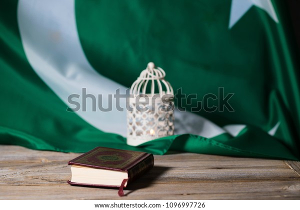 Moscow, Russia. 05/21/2018. Sacred book of Koran\
on a wooden surface. Flag of Pakistan in the background.\
Translation - book contains verses of\
Koran