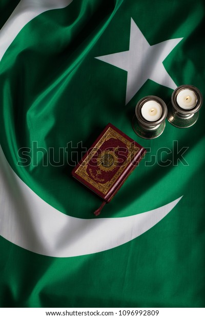 Moscow, Russia. 05/21/2018:Quran and candles on a\
flag of Pakistan. Translation into English - the book contains\
verses of Koran