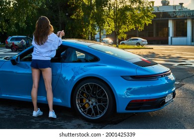 Moscow, Russia 07-02-02019 Porsche 911 Carrera 4S (Miami Blue) 992 Sports Beautiful Caucasian Woman Car Goes Away Into The Distance In The Sun And Sun Rays. Sports Car Is Driving In The Parking Lot. 