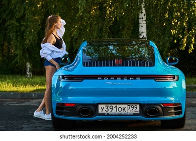 Moscow, Russia 07-02-02019 Porsche 911 Carrera 4S (Miami Blue) 992 Sports Beautiful Caucasian Woman Car Goes Away Into The Distance In The Sun And Sun Rays. Sports Car Is Driving In The Parking Lot. 