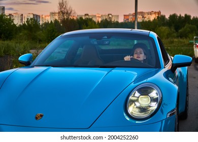 Moscow, Russia 07-02-02019 Porsche 911 Carrera 4S (Miami Blue) 992 Sports Beautiful Caucasian Woman Car Goes Away Into The Distance In The Sun And Sun Rays. Sports Car Is Driving In The Parking Lot. 