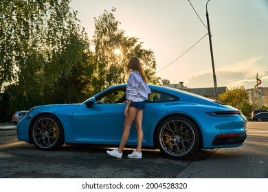 Moscow, Russia 07-02-02019 Porsche 911 Carrera 4S (Miami Blue) 992 Sports Beautiful Caucasian Woman Car Goes Away Into The Distance In The Sun And Sun Rays. Sports Car Is Driving In The Parking Lot. 