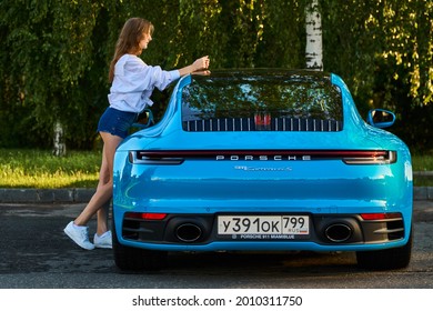 Moscow, Russia 07-02-02019 Porsche 911 Carrera 4S (Miami Blue) 992 Sports Beautiful Caucasian Woman Car Goes Away Into The Distance In The Sun And Sun Rays. Sports Car Is Driving In The Parking Lot. 