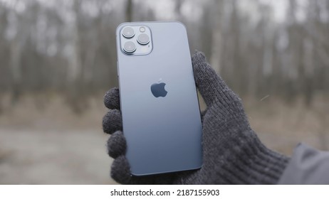 Moscow, Russia - 11.28.2020: Man Hand Holding Iphone Demonstrating Its Back Side. Action. New Apple Iphone 12 Pro Max In A Male Hand Outdoors.