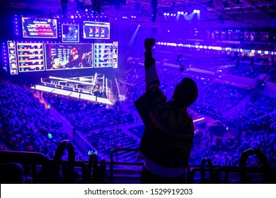 MOSCOW, RUSSIA - 14th SEPTEMBER 2019: Esports Video Games Event. Happy Dedicated Electronic Sports Fan Cheering For His Favorite Team On A Tribunes In Front Of A Big Screen With Hand Raised.