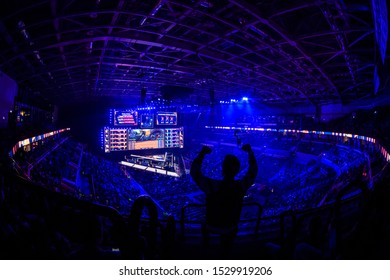 MOSCOW, RUSSIA - 14th SEPTEMBER 2019: esports video games event. Happy dedicated electronic sports fan cheering for his favorite team on a tribunes in front of a big screen with hands raised.