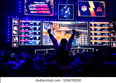 MOSCOW, RUSSIA - 14th SEPTEMBER 2019: Esports Gaming Event. Big Illuminated Main Stage And Screen And A Fan With A Hands Raised At Arena.