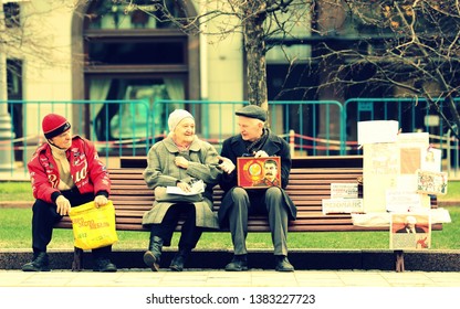 Moscow Russia 15 September 2014. Old Bench On Square Bolshoi Theatre. 3 Elderly Russians Remembering The Old Soviet Union With Memorabilia. Two Men One Woman Dress Is Old Style. Frame Of Stalin