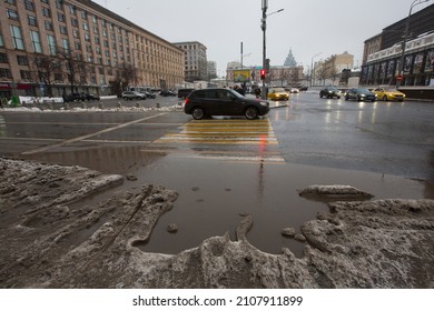 MOSCOW, RUSSIA 23.01.2021 Dirty Grey Black Wet Sloppy Melting Snow, Slush And Ooze, Big Puddle On Asphalt Road With Cars And People On Pedestrian Crosswalk. Depressing Winter Thaw. Maykovskaya Square